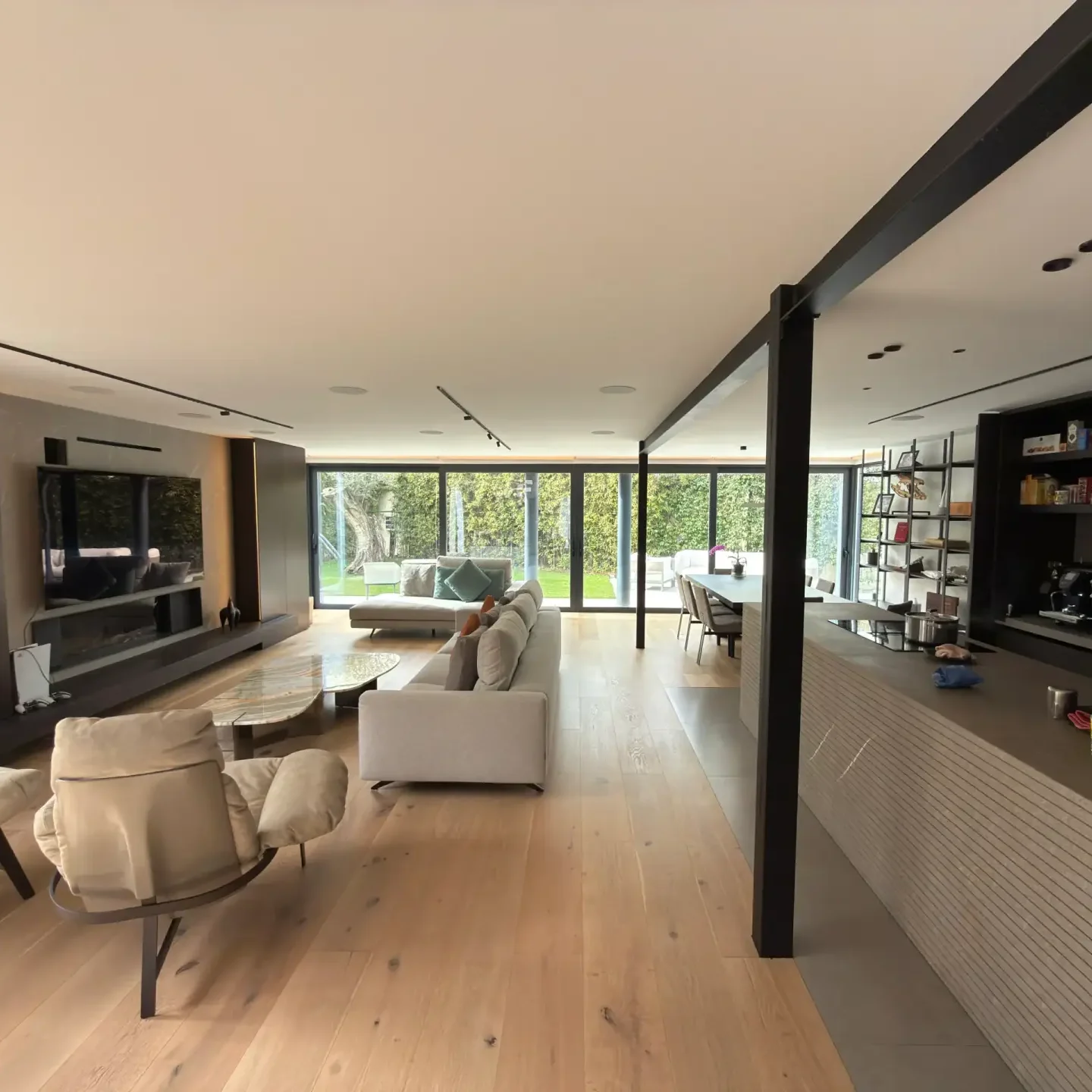 Salón comedor de concepto abierto con suelo de madera y vistas al jardín en chalet de Madrid.
