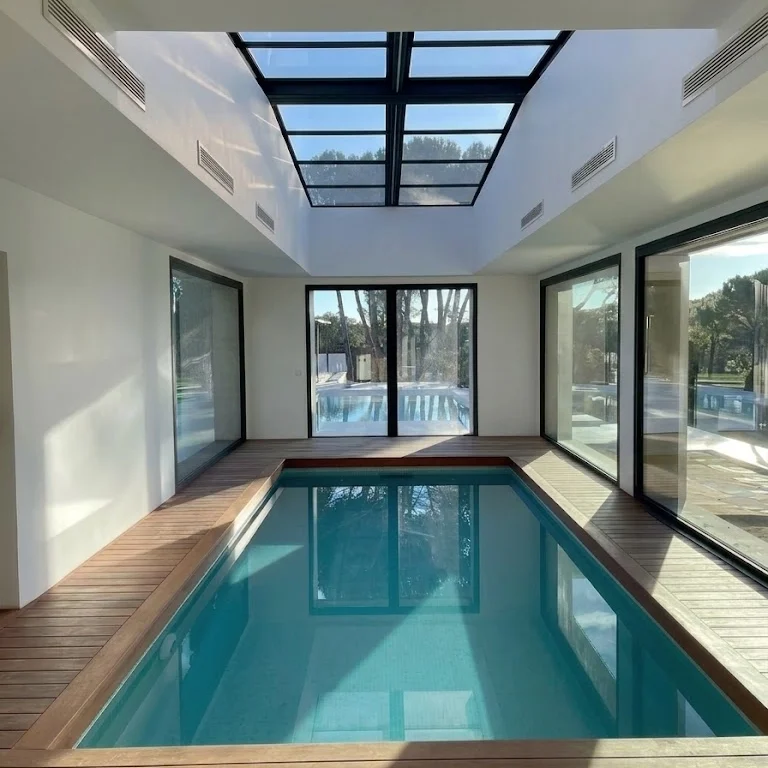 Piscina de obra climatizada con tarima de madera y cerramiento acristalado construida en Madrid.