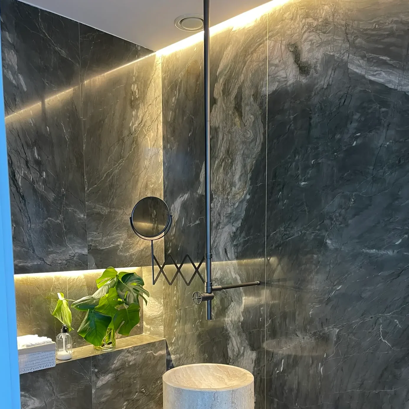 Aseo de diseño de lujo con lavabo de piedra natural exento, espejo retroiluminado y paredes texturizadas.