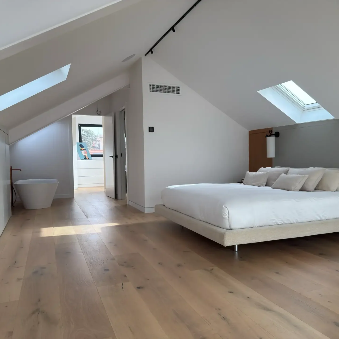 Habitación principal de diseño moderno en ático abuhardillado reformada integralmente en Madrid.