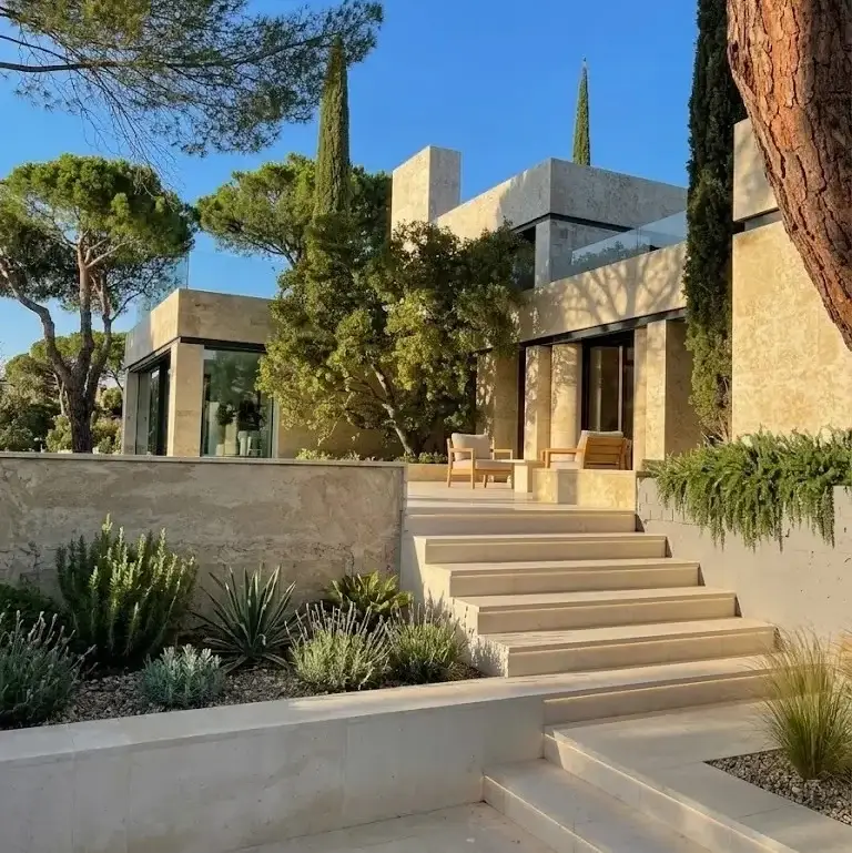Fachada de chalet exclusivo revestida de piedra con escaleras de acceso y proyecto de paisajismo en Pozuelo de Alarcón.