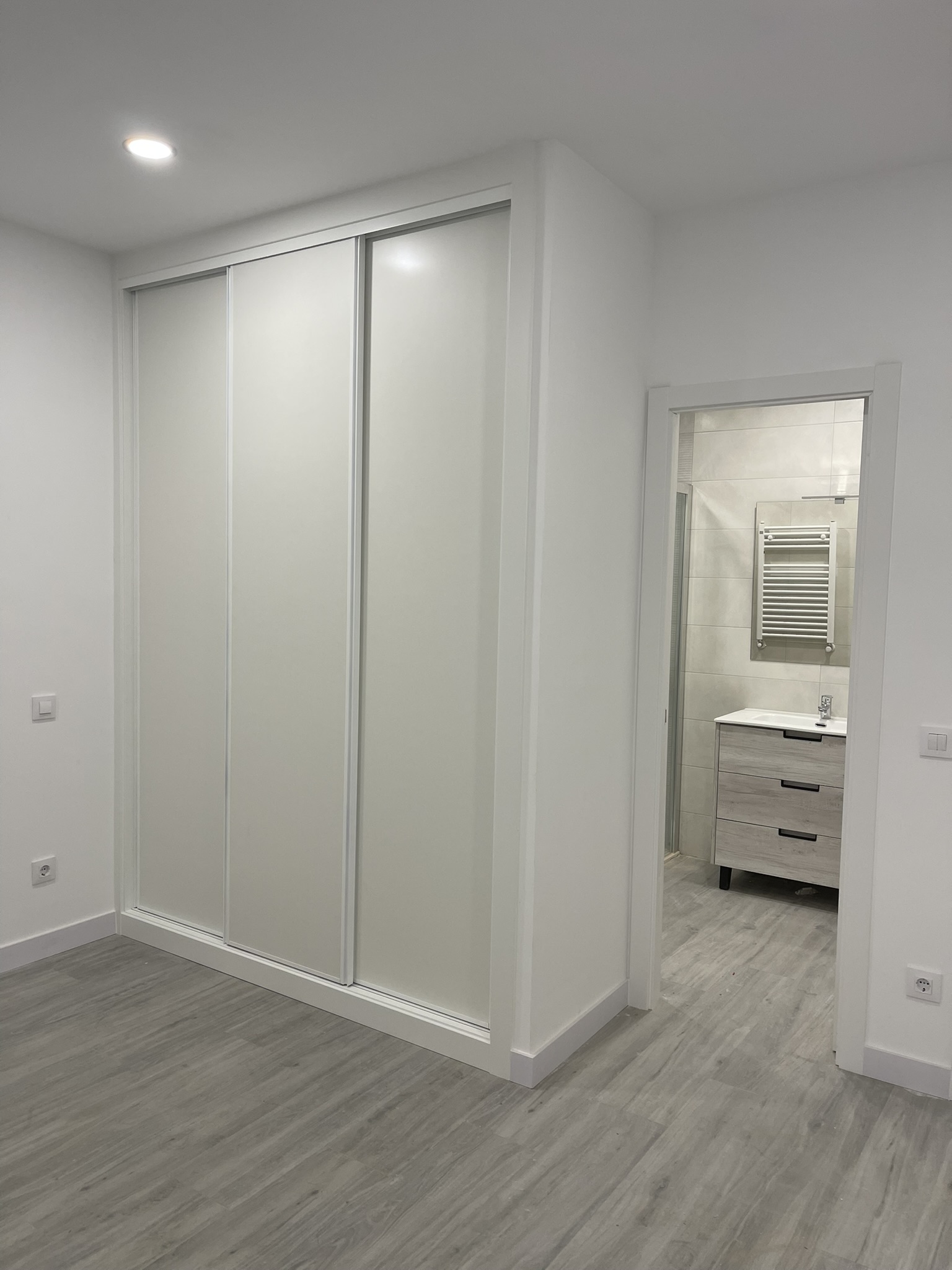 Acabados de dormitorio con armario empotrado y puerta de acceso a baño en suite reformado