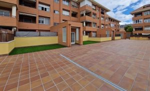 Pavimento exterior con canaletas de drenaje pluvial en patio comunitario de Madrid