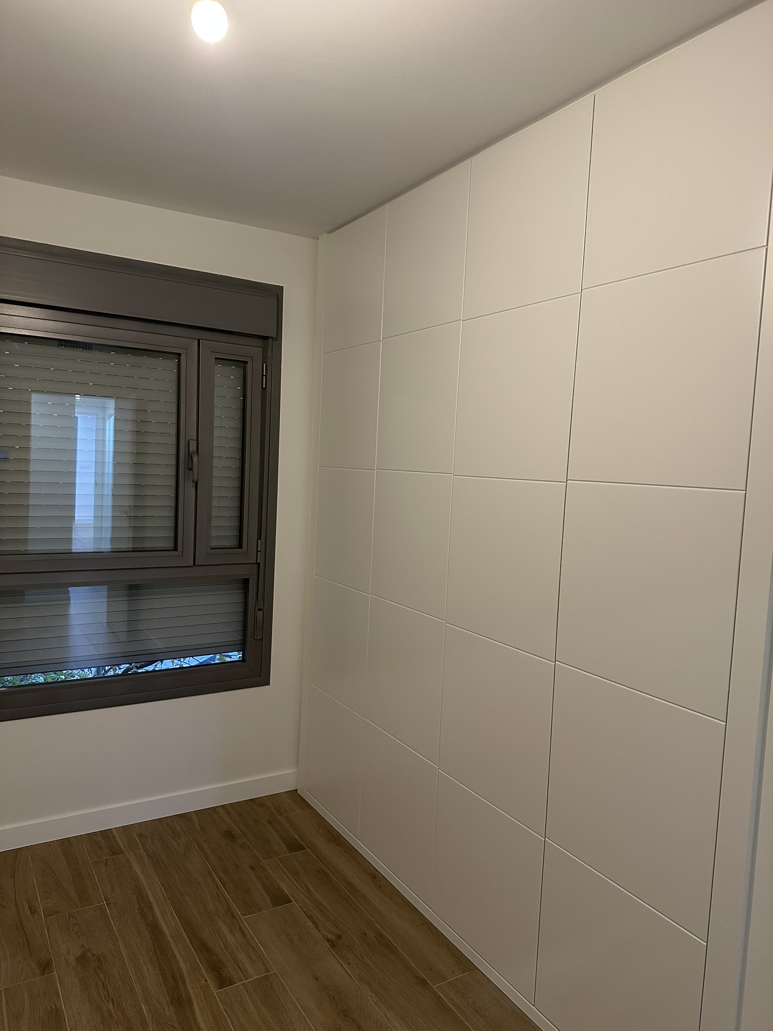 Dormitorio reformado con armario empotrado blanco a medida y ventana oscilobatiente en Madrid