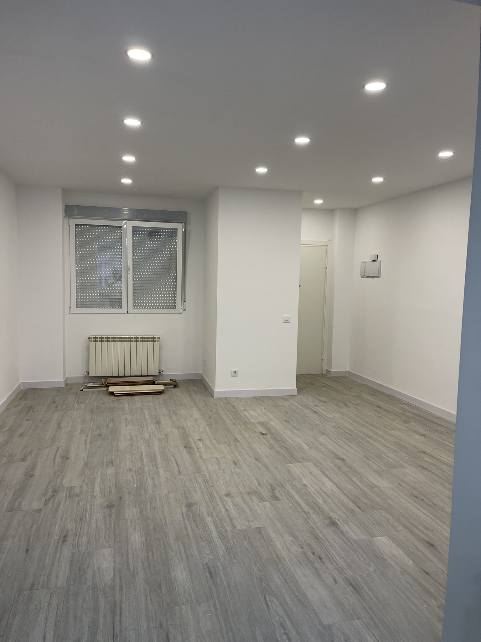 Salón diáfano con iluminación por focos LED empotrados y suelo laminado en Madrid