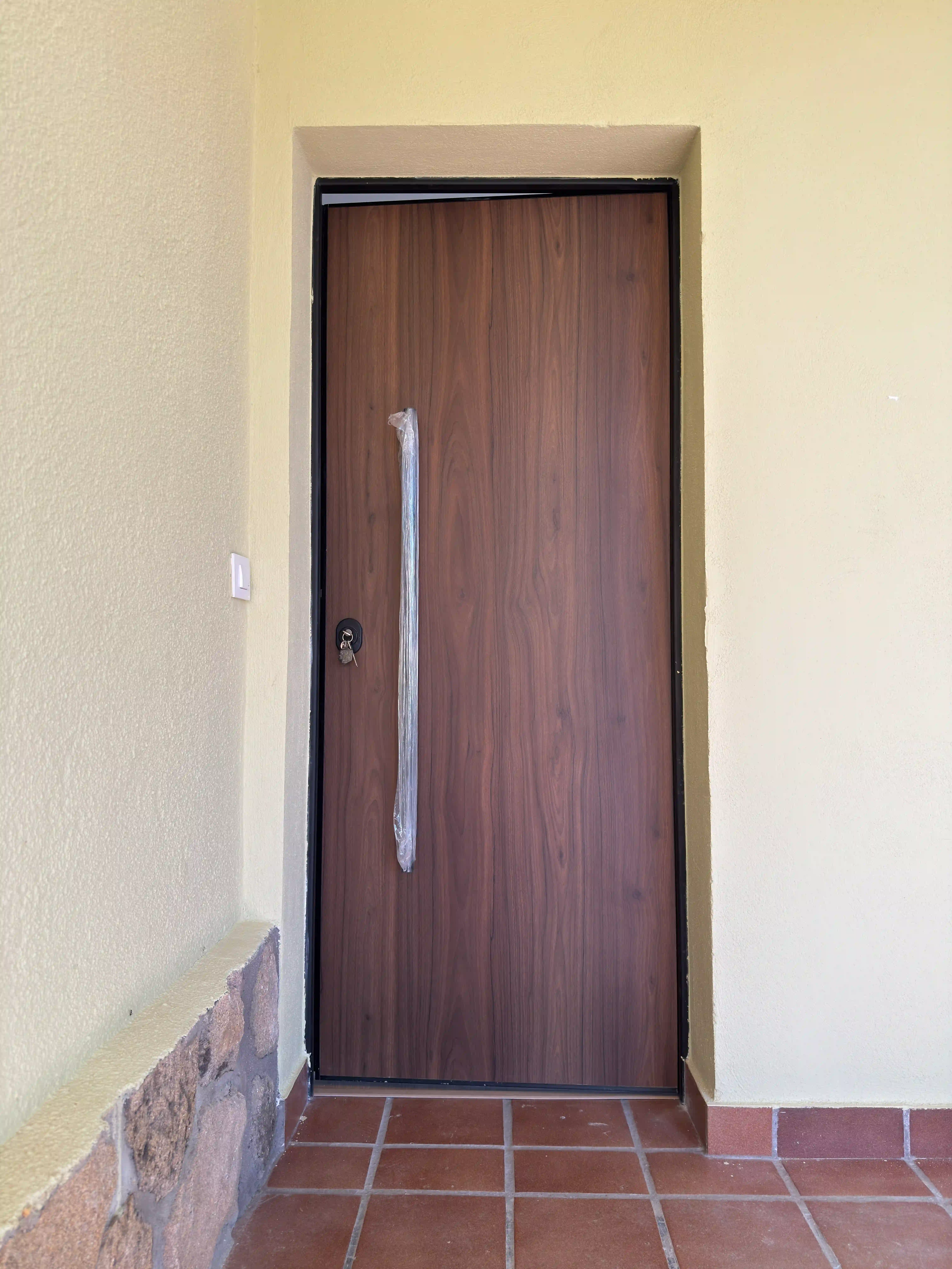 Nueva puerta de entrada principal acabada en madera instalada en la vivienda reformada.