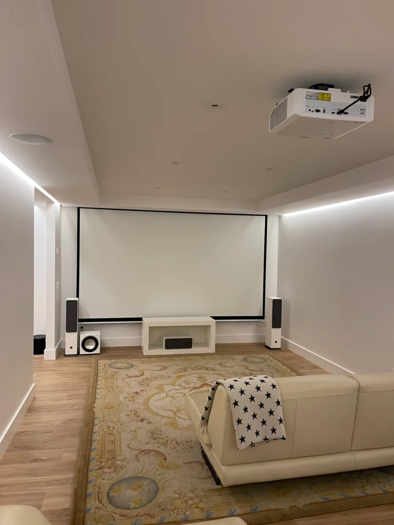 Sala de cine en casa con pantalla de gran formato, iluminación LED perimetral y acondicionamiento acústico premium.