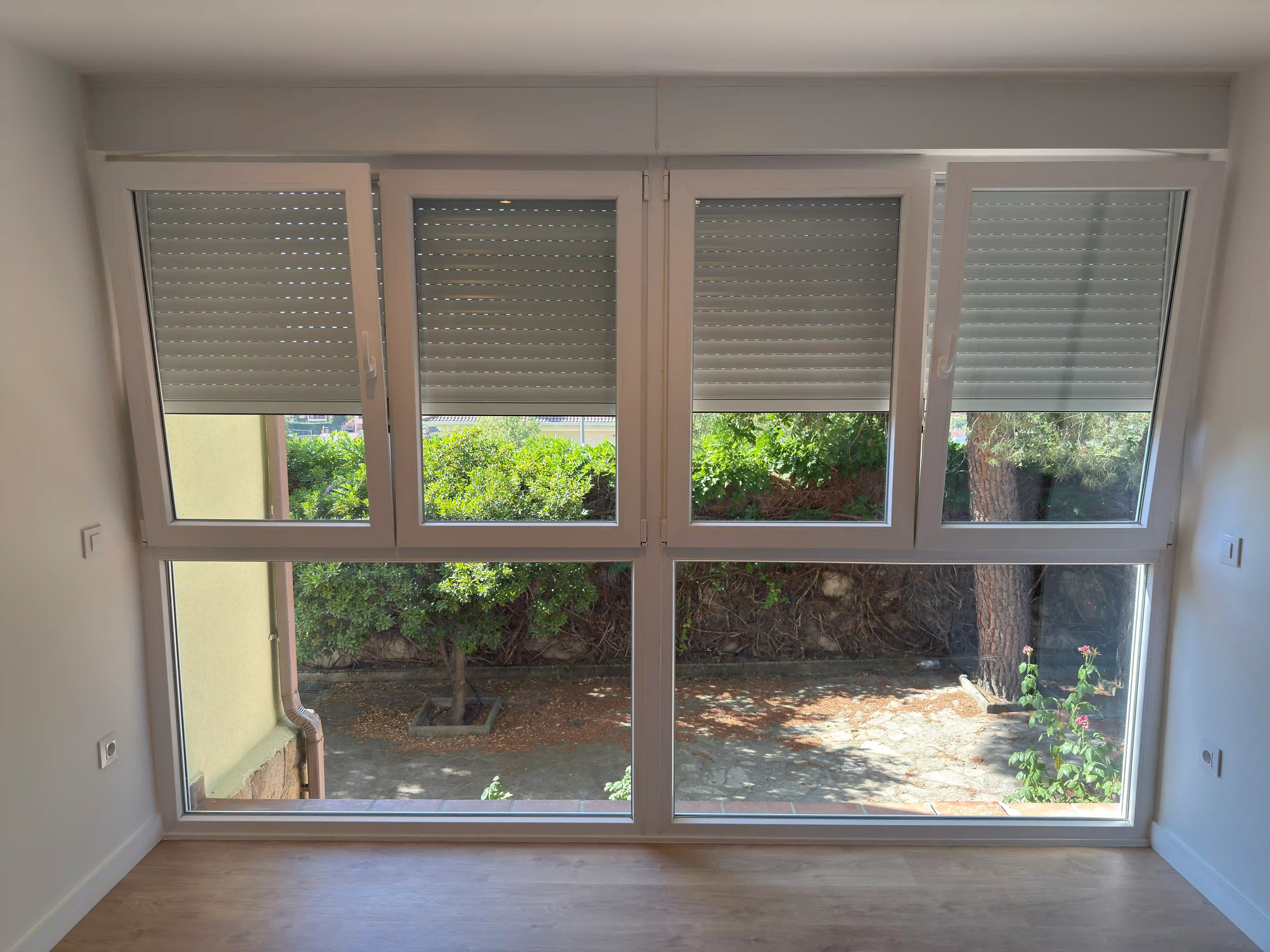 Ventanas panorámicas de PVC de última generación y persianas motorizadas con vistas al exterior.