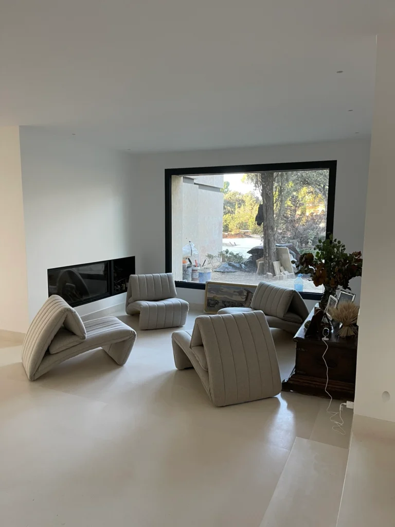 Espacio de salón minimalista con grandes ventanales de perfilería oculta y vistas directas al jardín en rehabilitación integral.