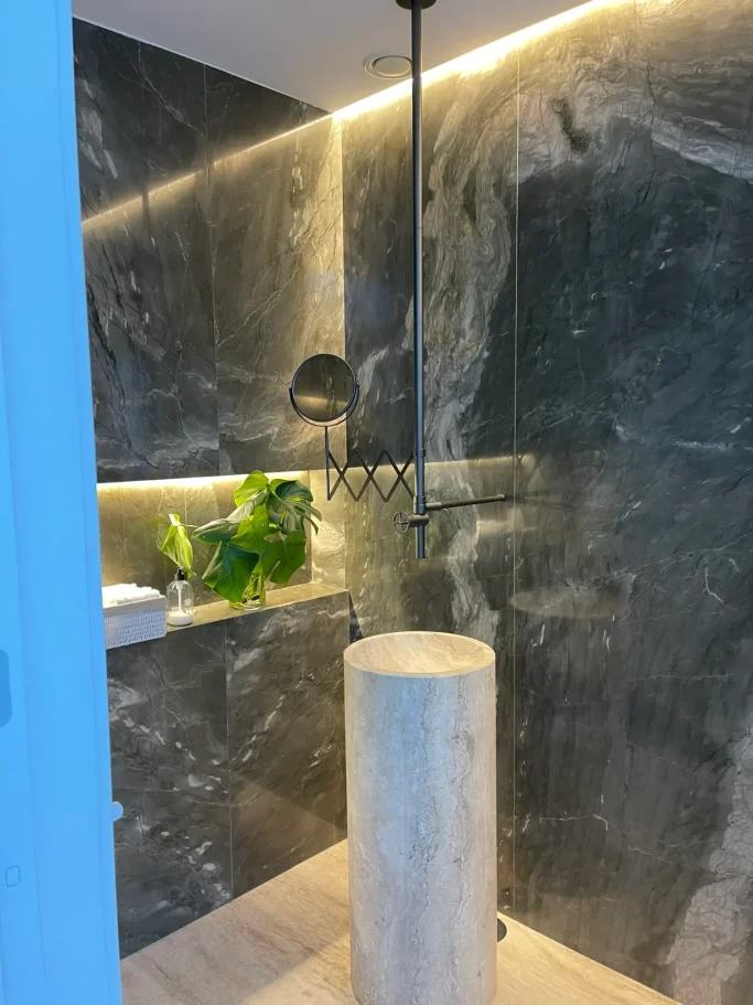 Acabados de Baño en Mármol Premium Detalle de reforma de baño de lujo revestido en mármol con grifería empotrada por Valandecor.